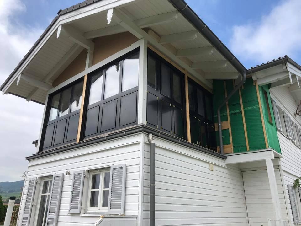 Une maison blanche avec des fenêtres noires et des volets verts