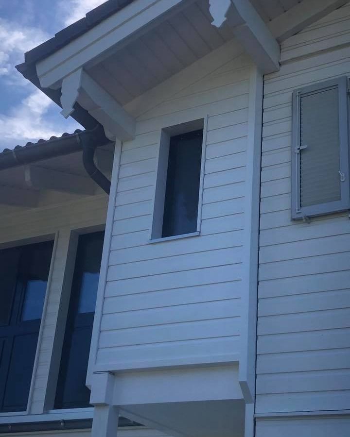 Une maison blanche avec une porte et une fenêtre noires