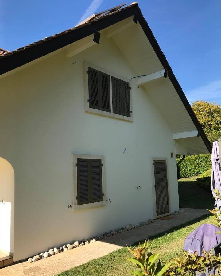 Une maison blanche avec des volets marron aux fenêtres