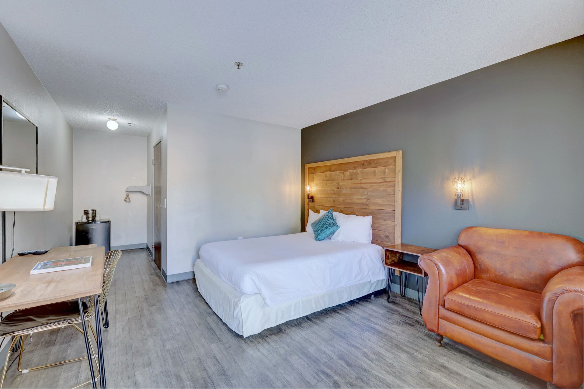 A hotel room with a bed , chair , desk and television.