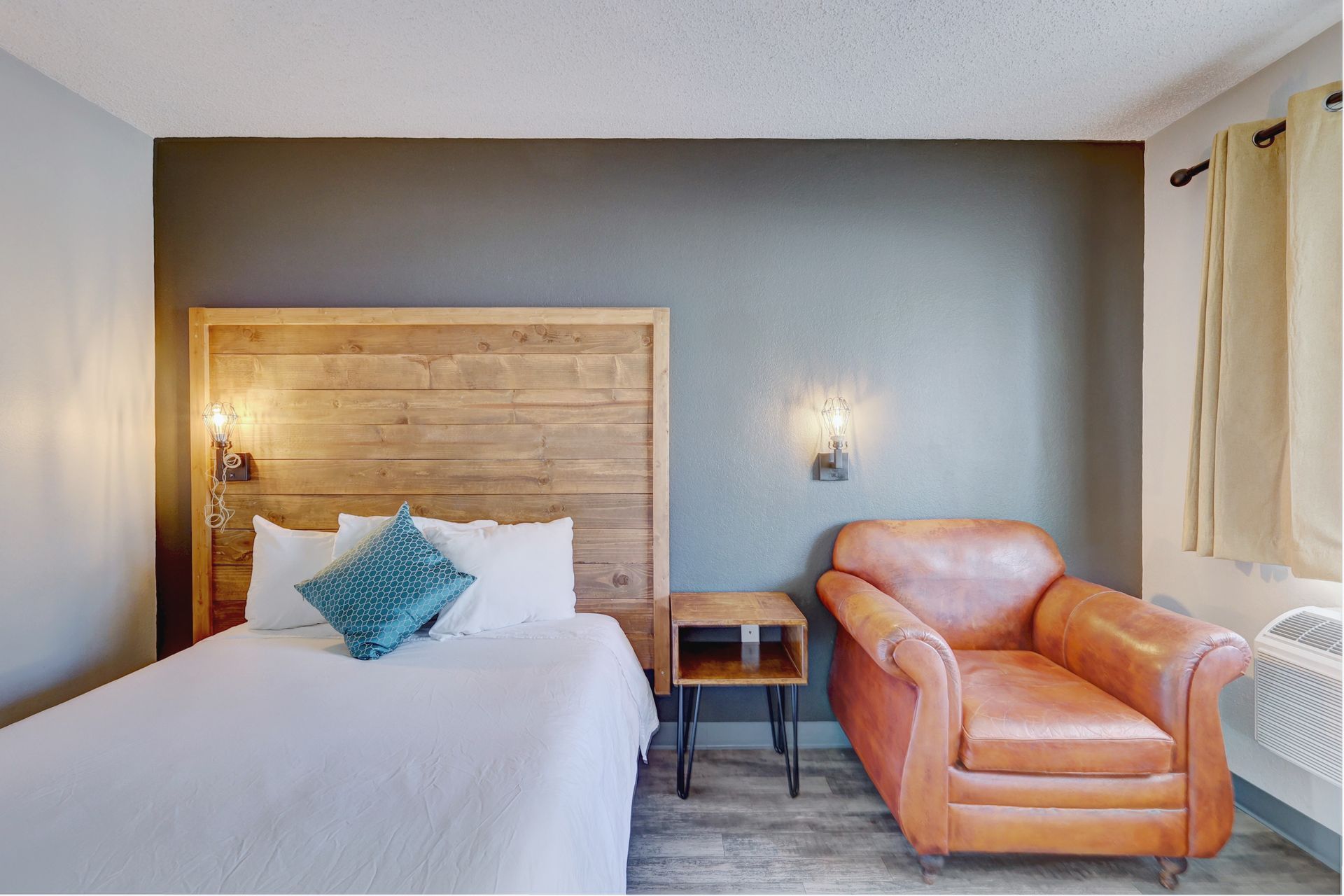 A hotel room with a bed , chair and nightstand.