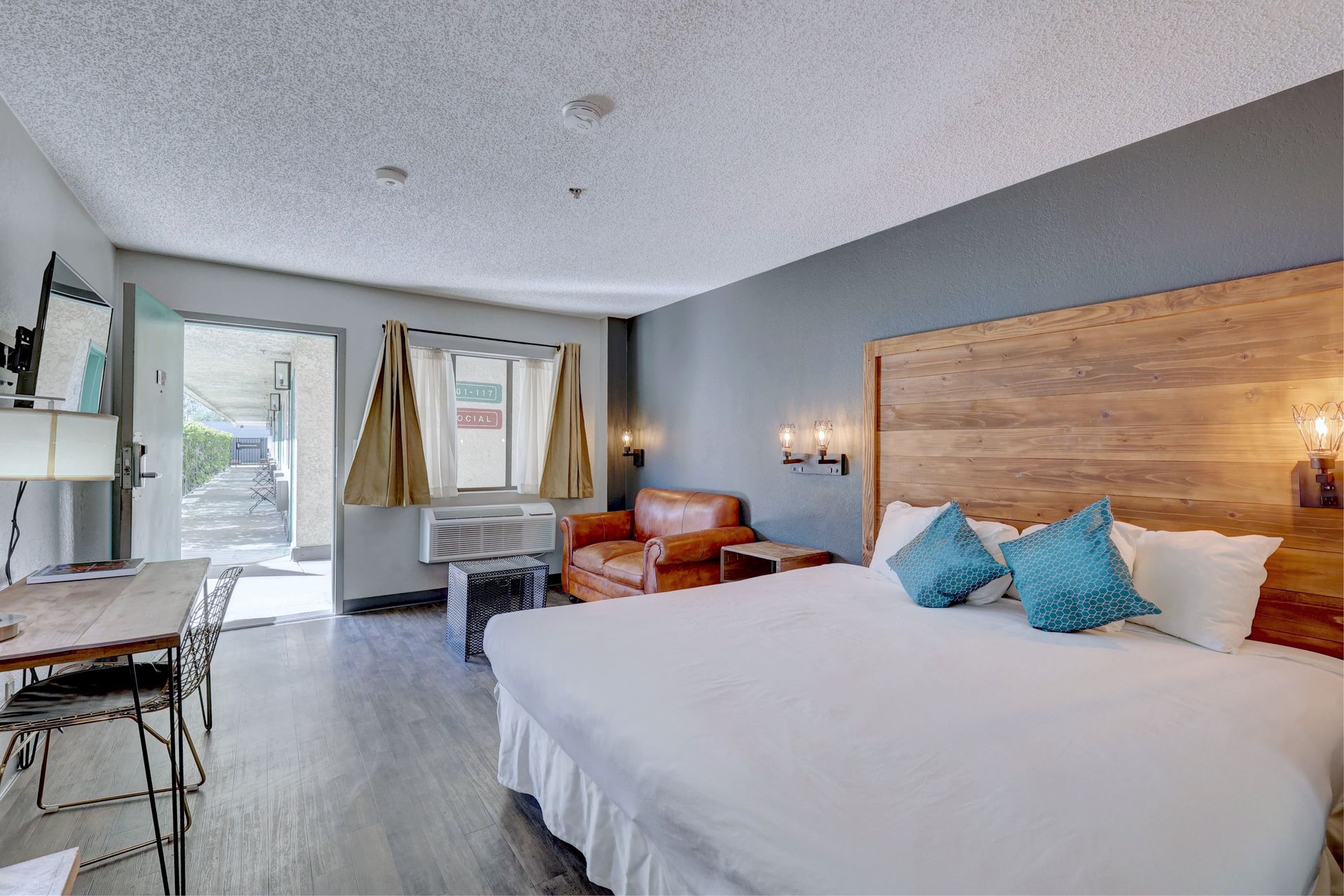 A hotel room with a king size bed , chair , desk and television.