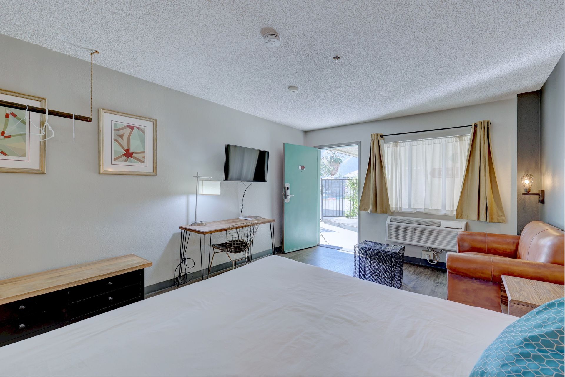 A hotel room with a king size bed , chair , desk and television.