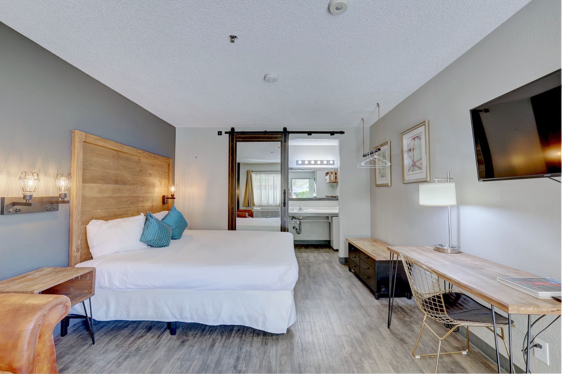 A hotel room with a king size bed , desk , chair and television.