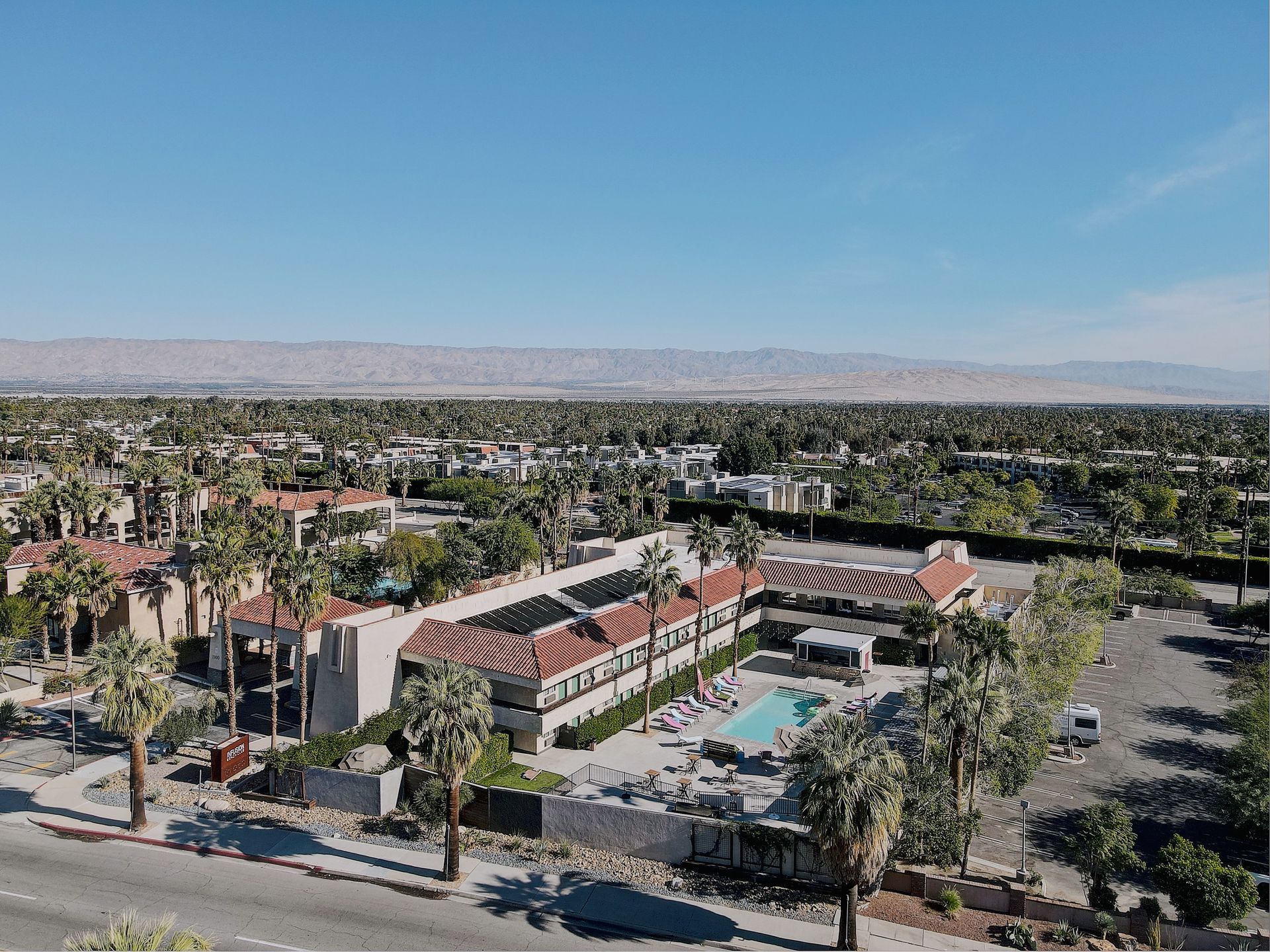 An aerial view of a hotel with a pool and palm trees.