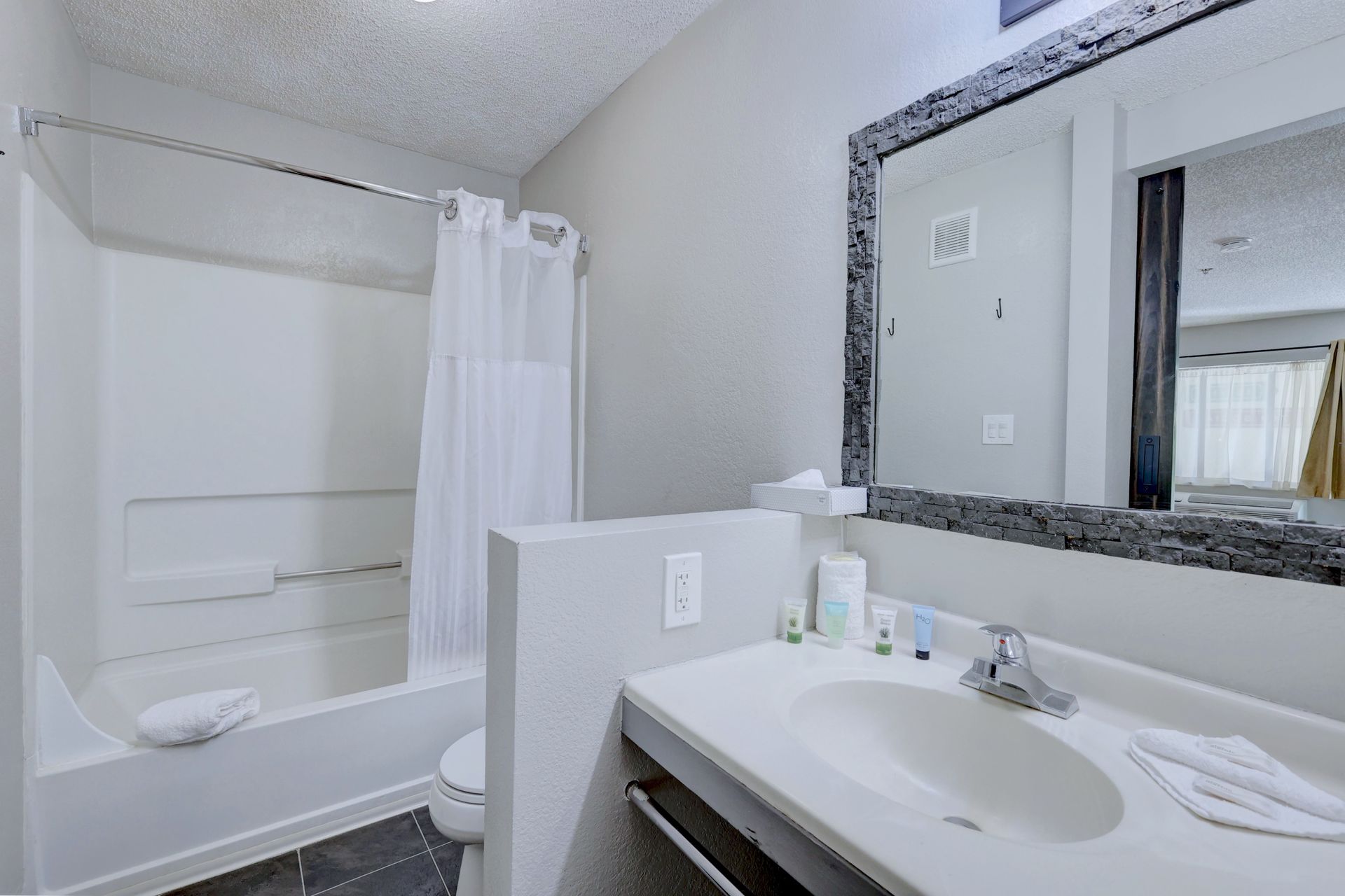 A bathroom with a sink , toilet , shower and mirror.