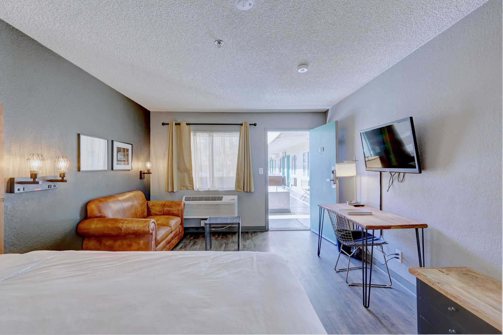 A hotel room with a bed , couch , desk and television.