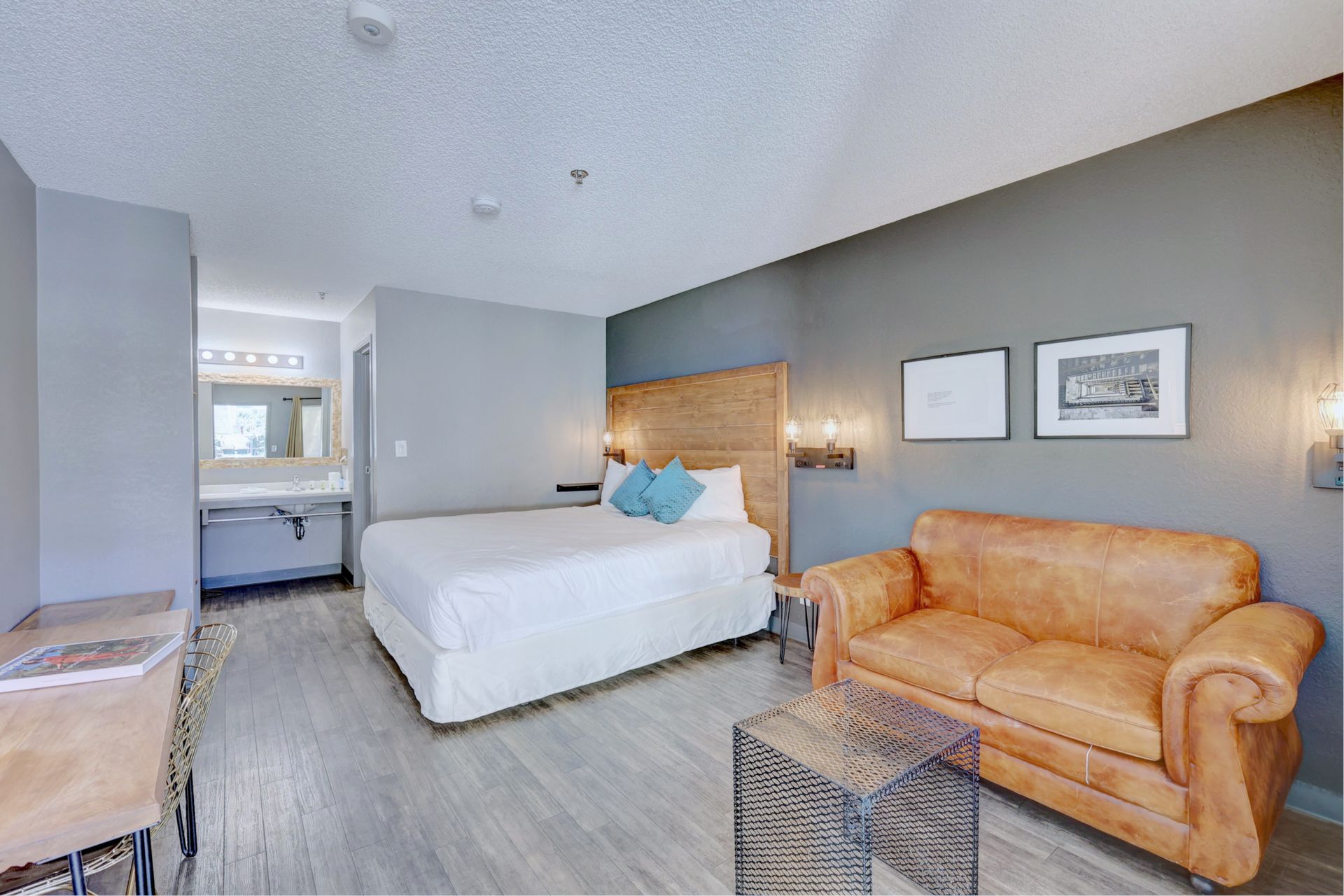 A hotel room with a king size bed , couch , desk and chairs.
