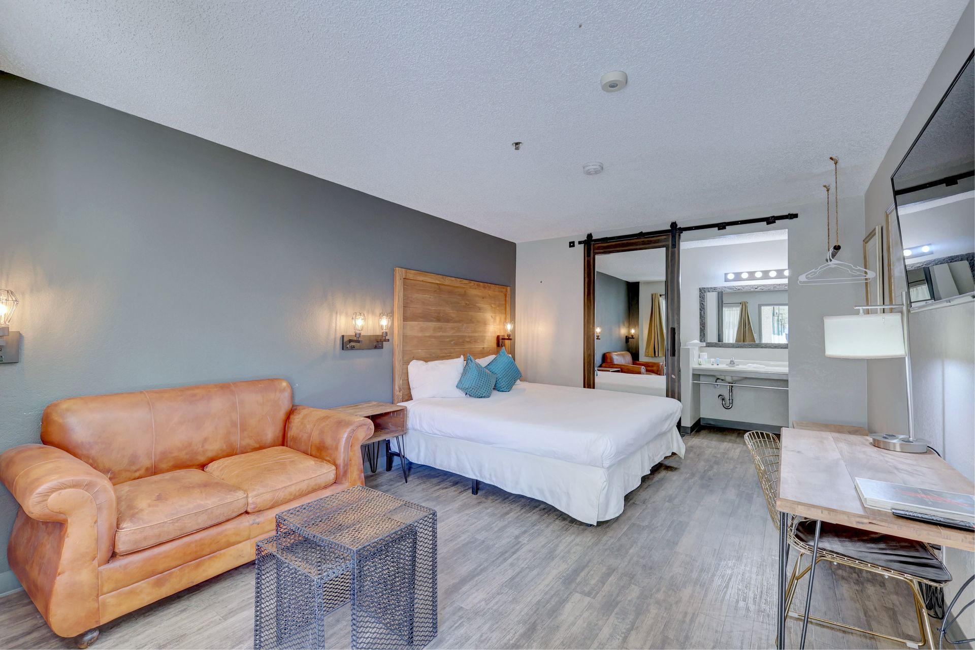 A hotel room with a king size bed , couch , desk and chairs.