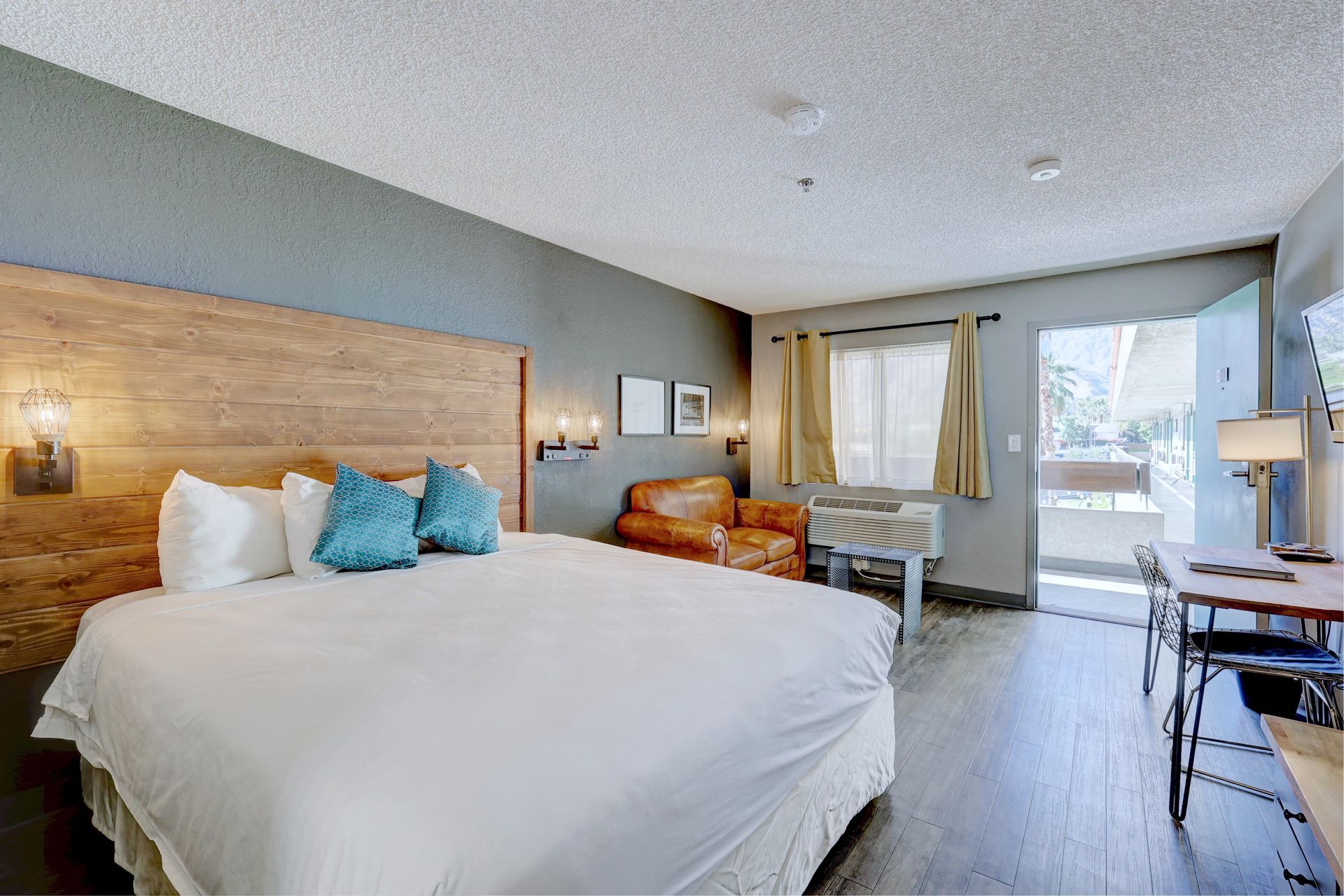 A hotel room with a king size bed , desk , chair and couch.