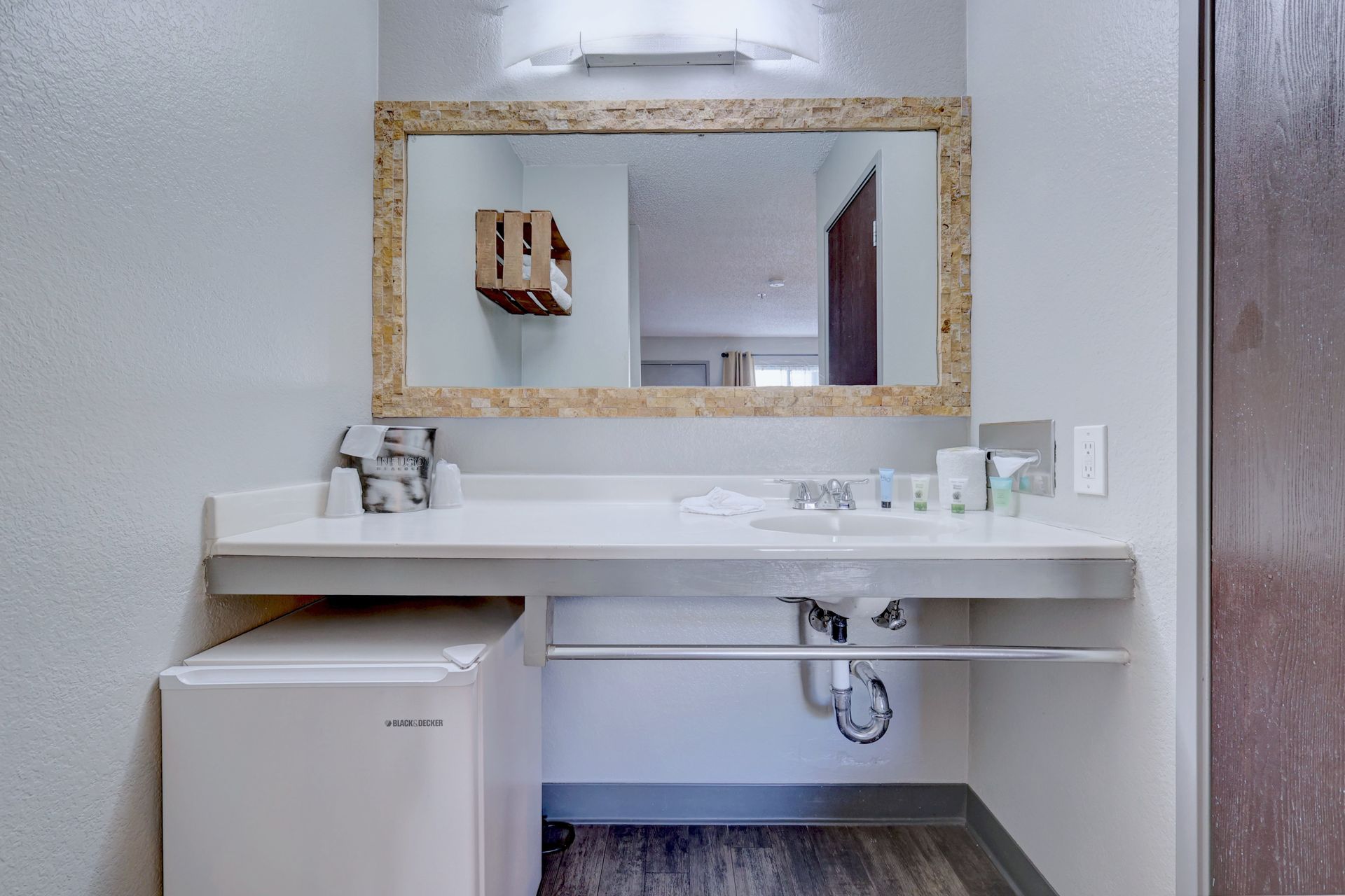 A bathroom with a sink , mirror and refrigerator.