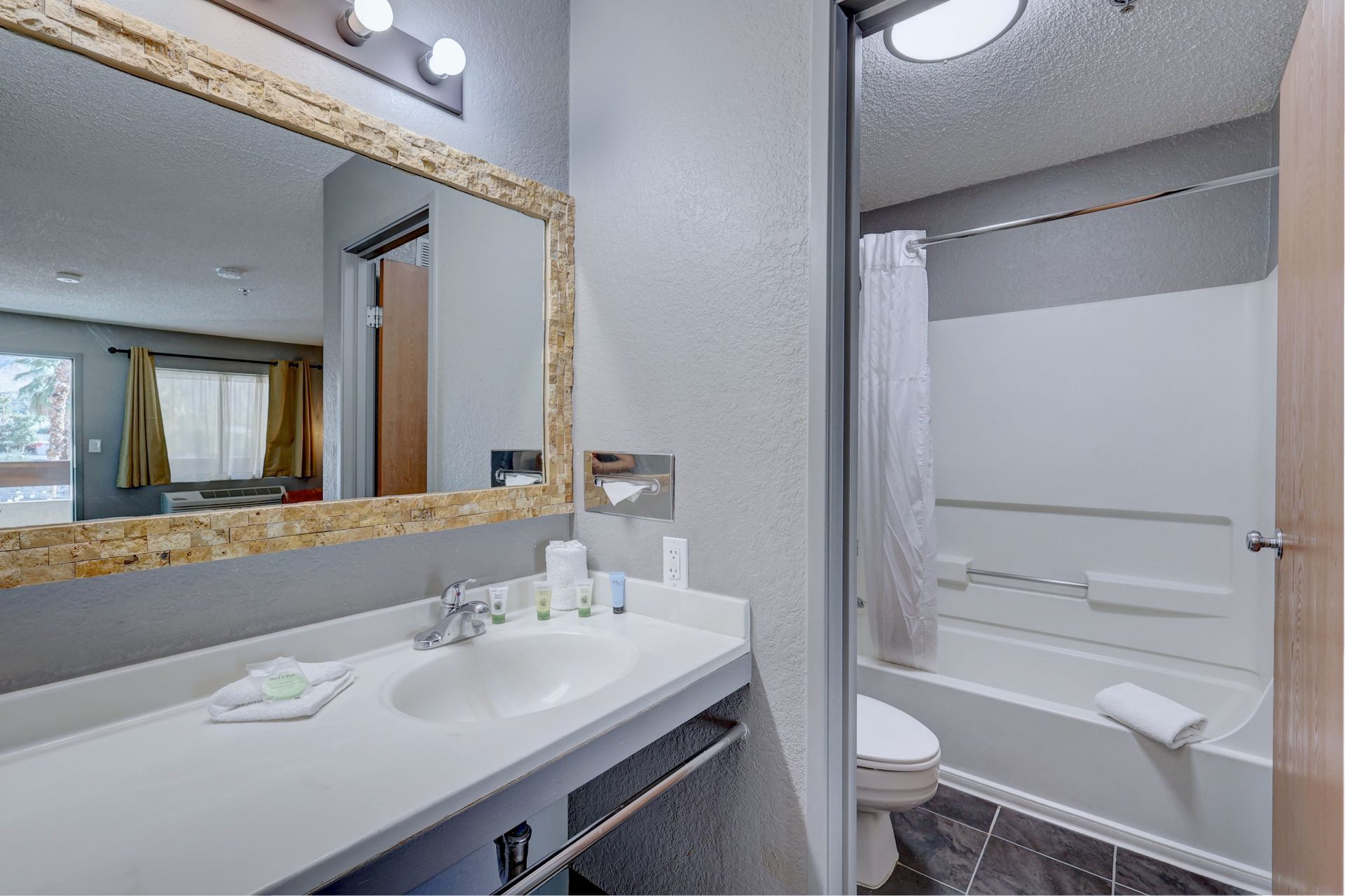 A bathroom with a sink , toilet , tub and mirror.