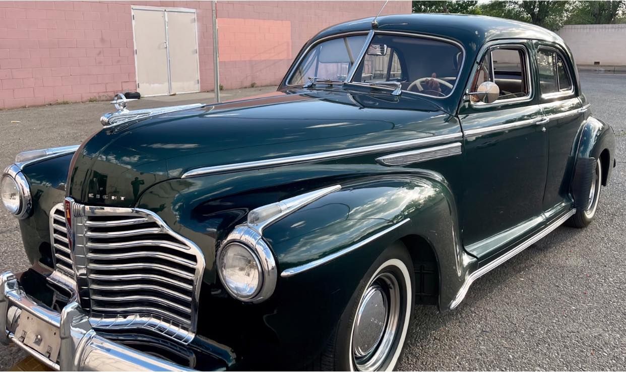 Green vintage Buick car with chrome accents parked outdoors.