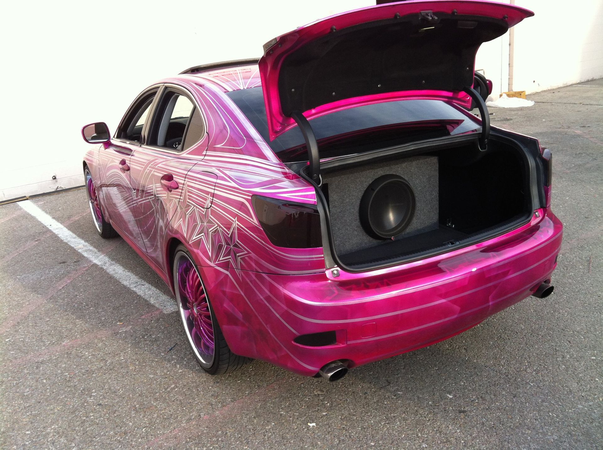 Pink car with open trunk and large subwoofer.