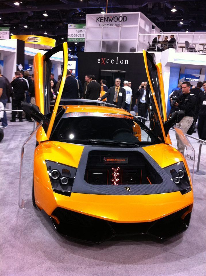 Orange Lamborghini with open doors at an event.