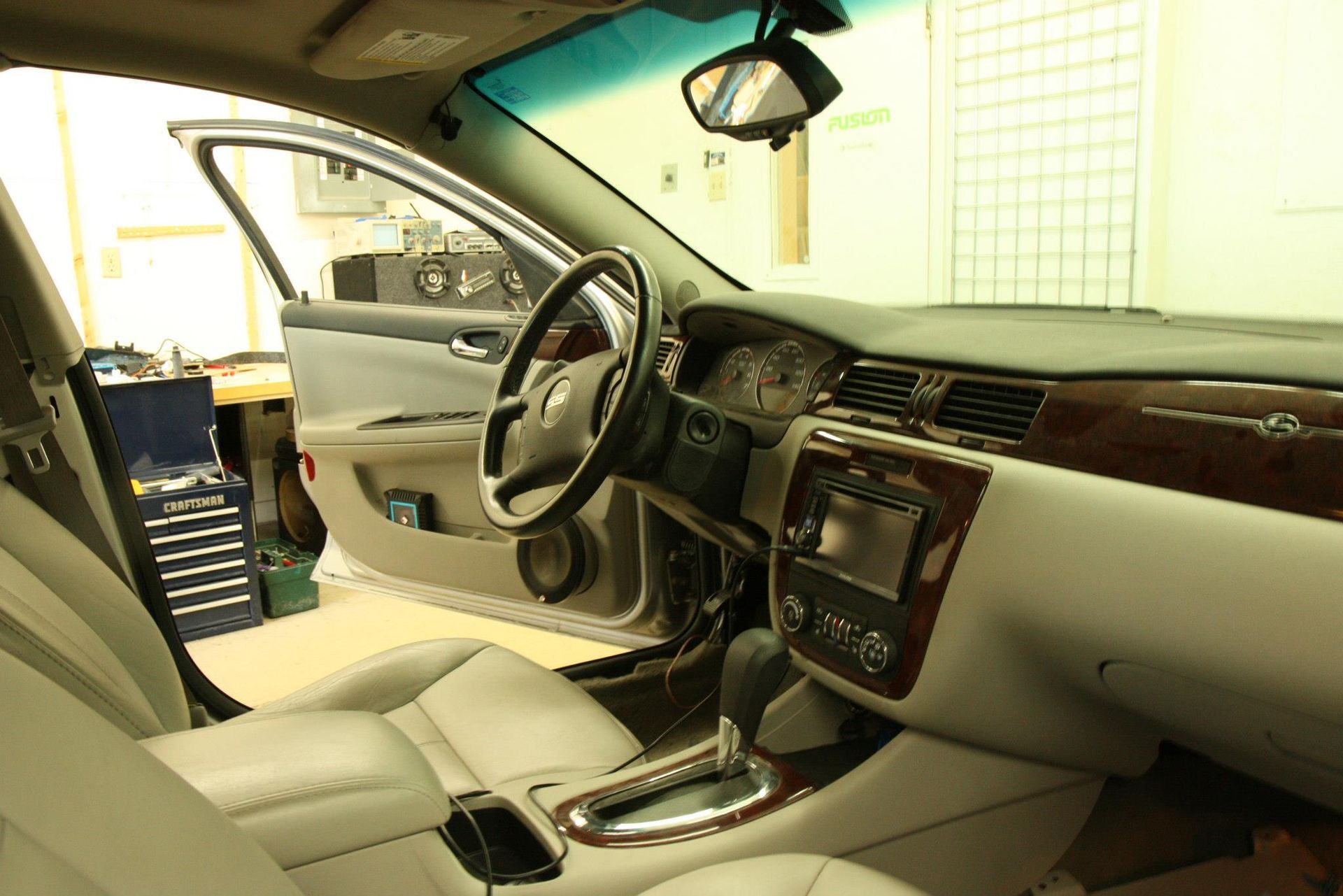 Interior of a car with exposed door panel, dashboard, steering wheel, and partially visible tools.