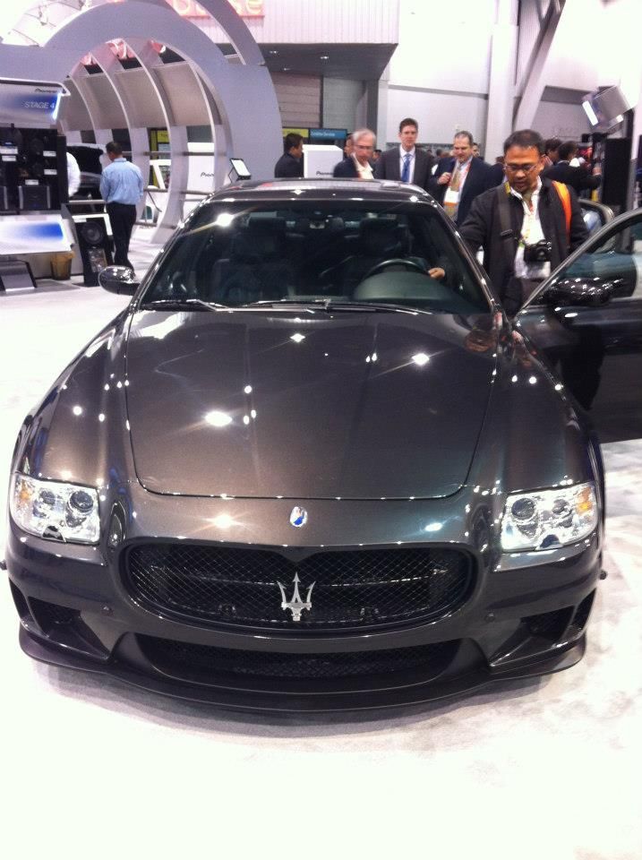 Dark gray Maserati at a car show, with people in the background.