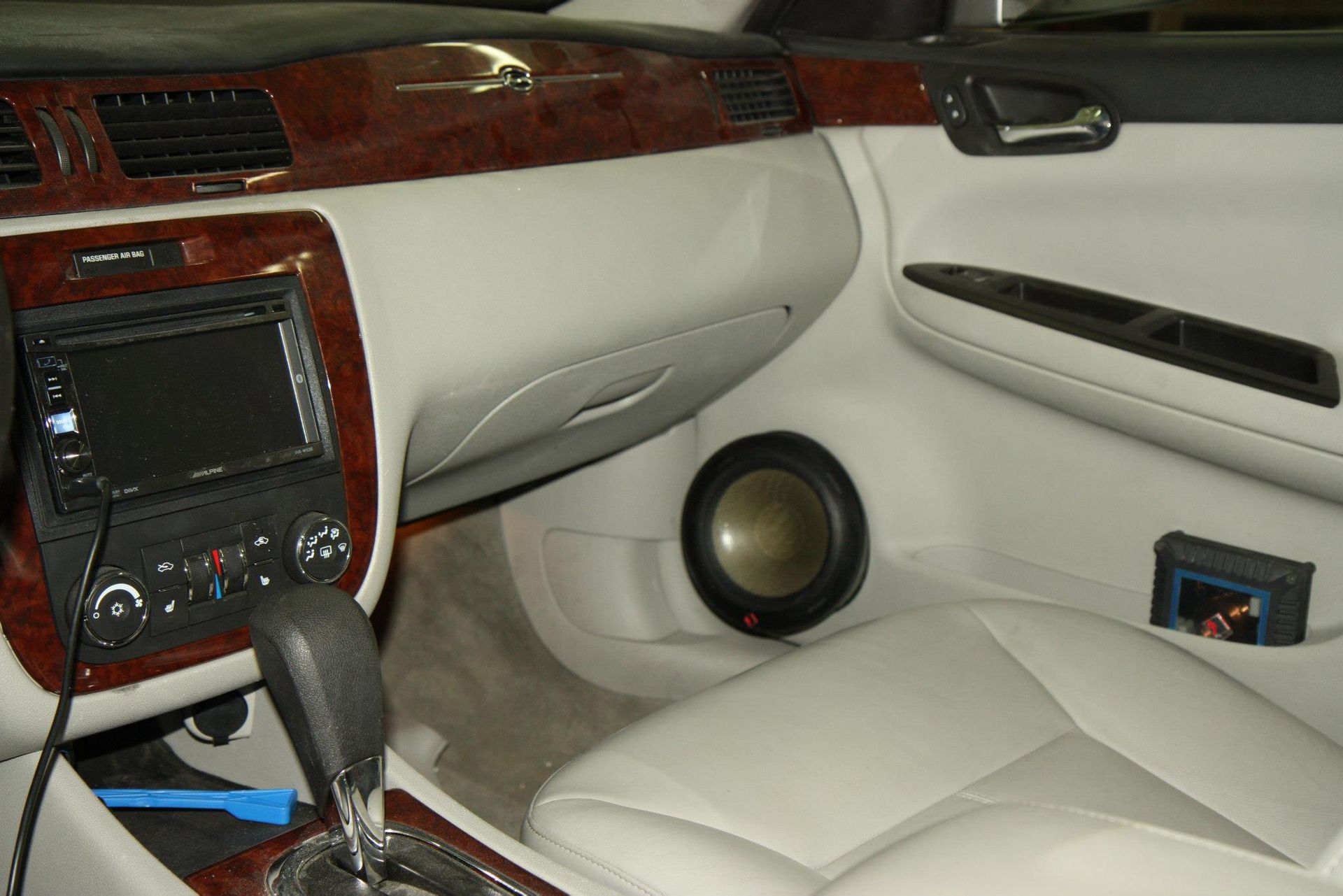 Car interior with dashboard, stereo, and speaker in passenger side footwell.