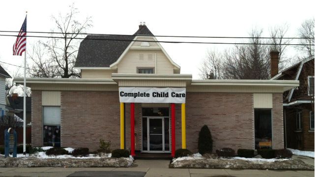 Complete Child Care building with front entrance, brick facade, and American flag in front.
