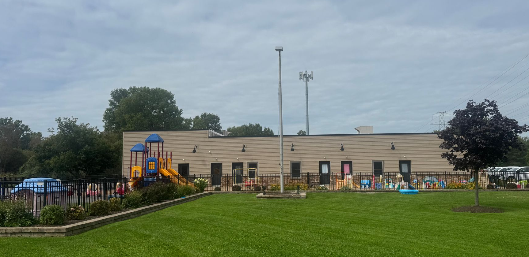 Childcare building with playground, flagpole, and cloudy sky