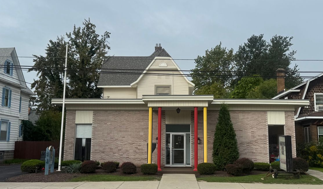 Complete Child Care building with front entrance, brick facade, and American flag in front.