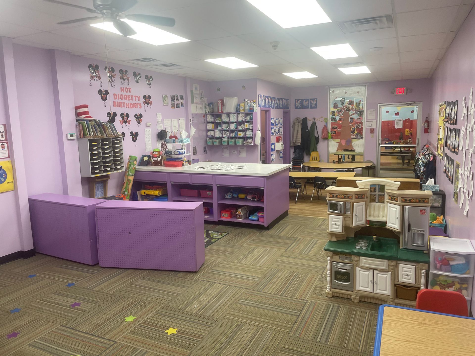 Purple classroom with tables, shelves, and learning materials in a brightly lit room