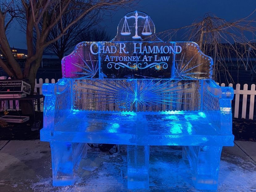 Ice sculpture of a bench with an attorney's name and scales of justice; lit with blue light. Ice sculpture of a bench with an attorney's name and scales of justice; lit with blue light.