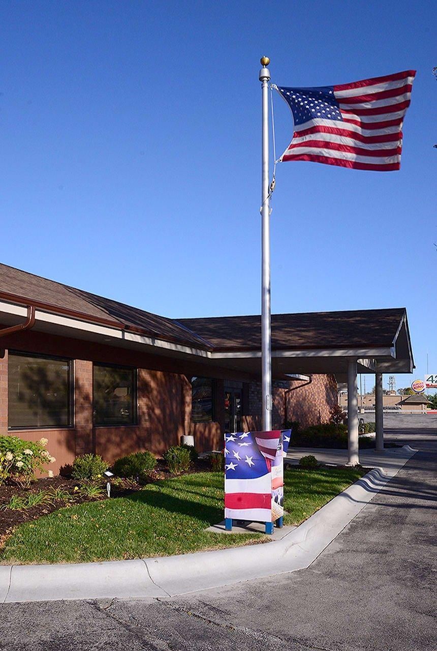 American flag on a pole outside a brick building under a clear blue sky