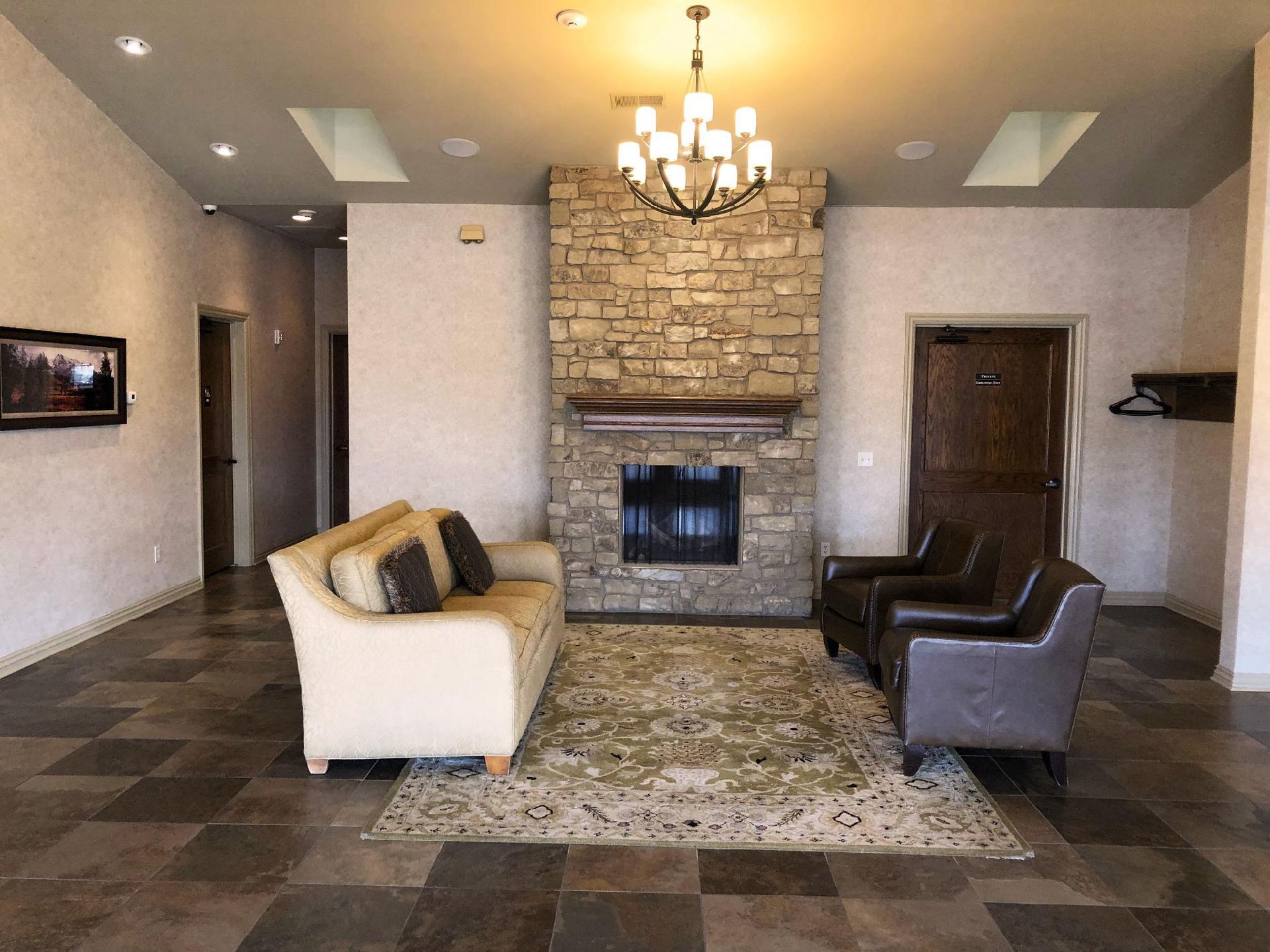 Modern living room with stone fireplace, chandelier, neutral sofas, and patterned rug