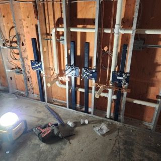 Wall framing in a building under construction, featuring four plumbing valve installations mounted on vertical metal studs.