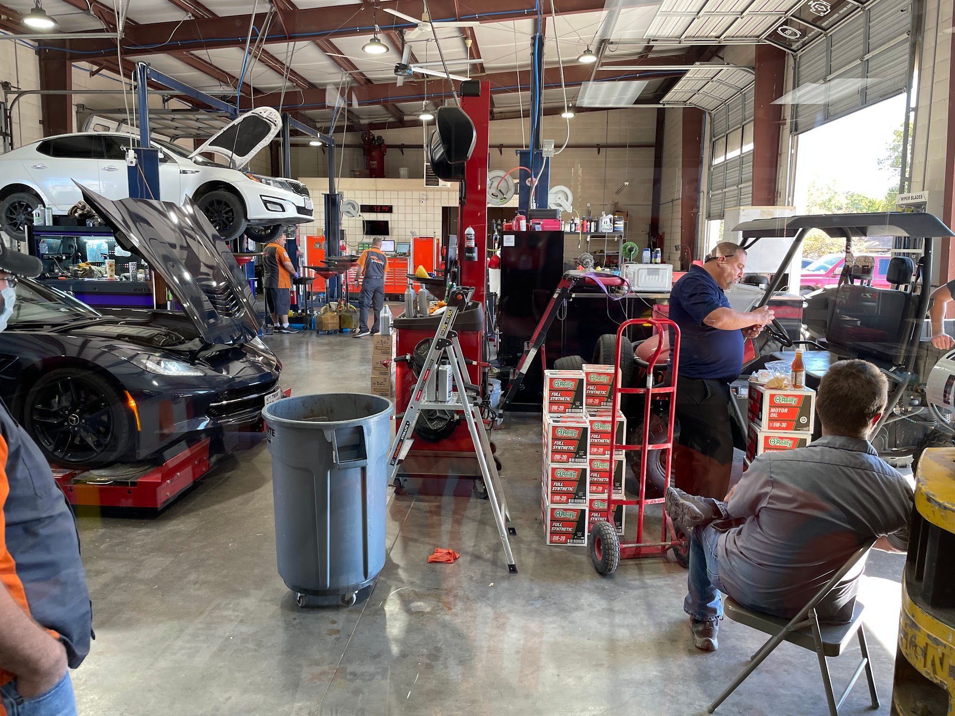 Auto repair shop with cars on lifts, mechanics working, tools and supplies. | Adam’s Auto Repair Shop