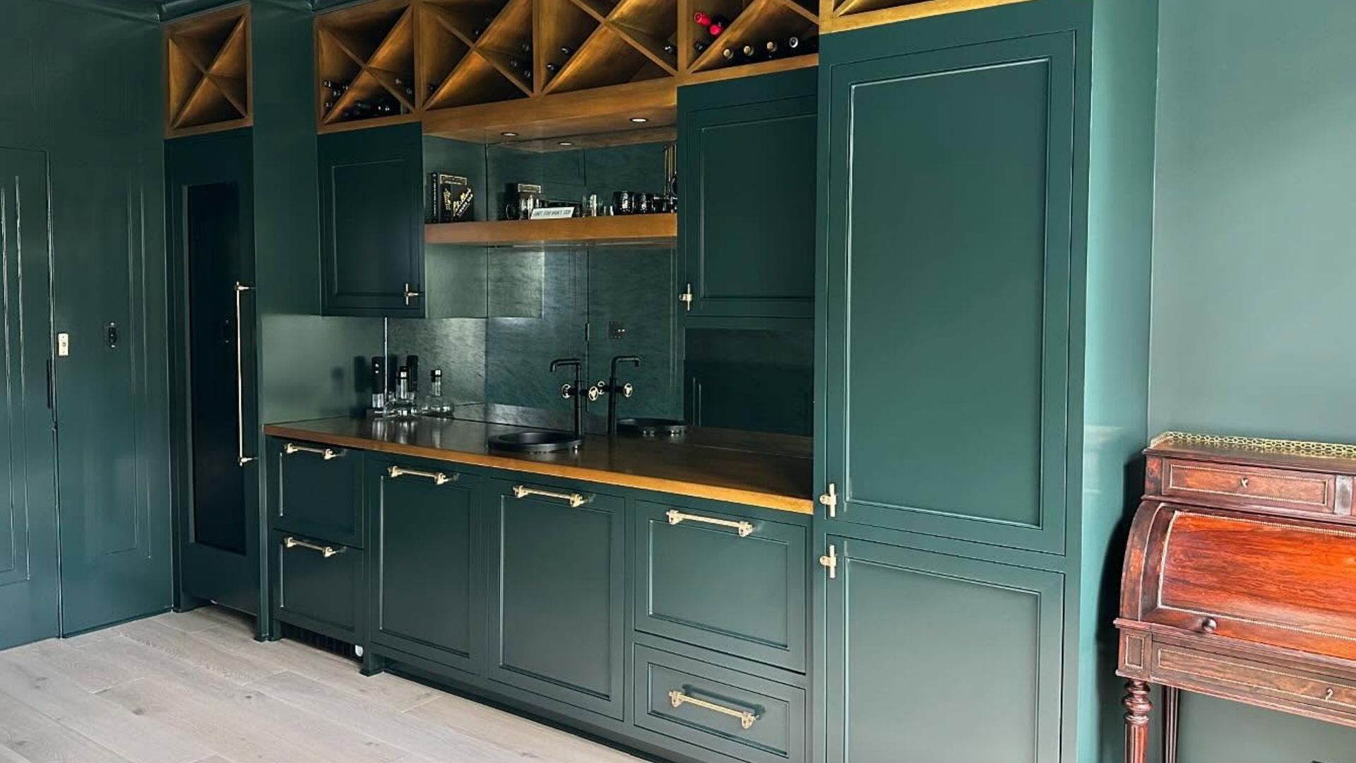 Teal built-in kitchen cabinets with sink, countertop, and open cubby shelves in a modern room