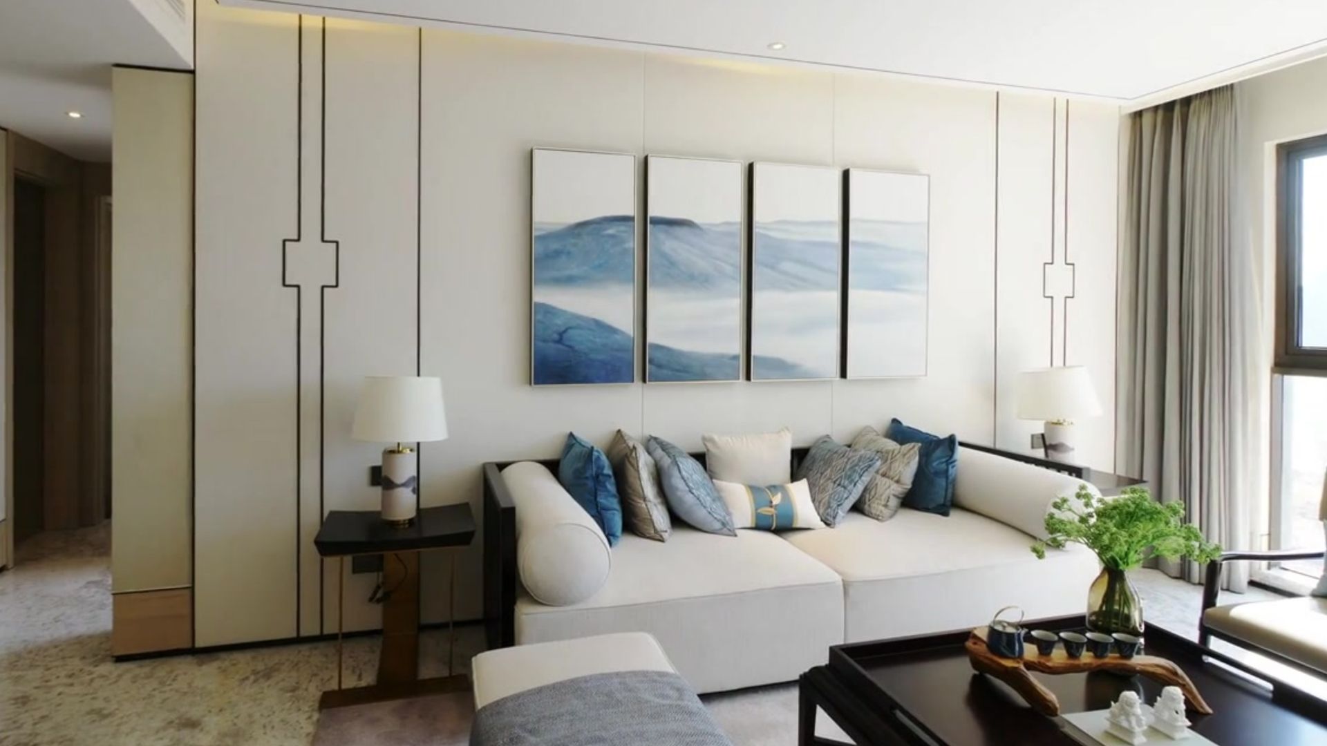 Modern living room with white sofa, blue wall art, floor lamp, and coffee table with plant.