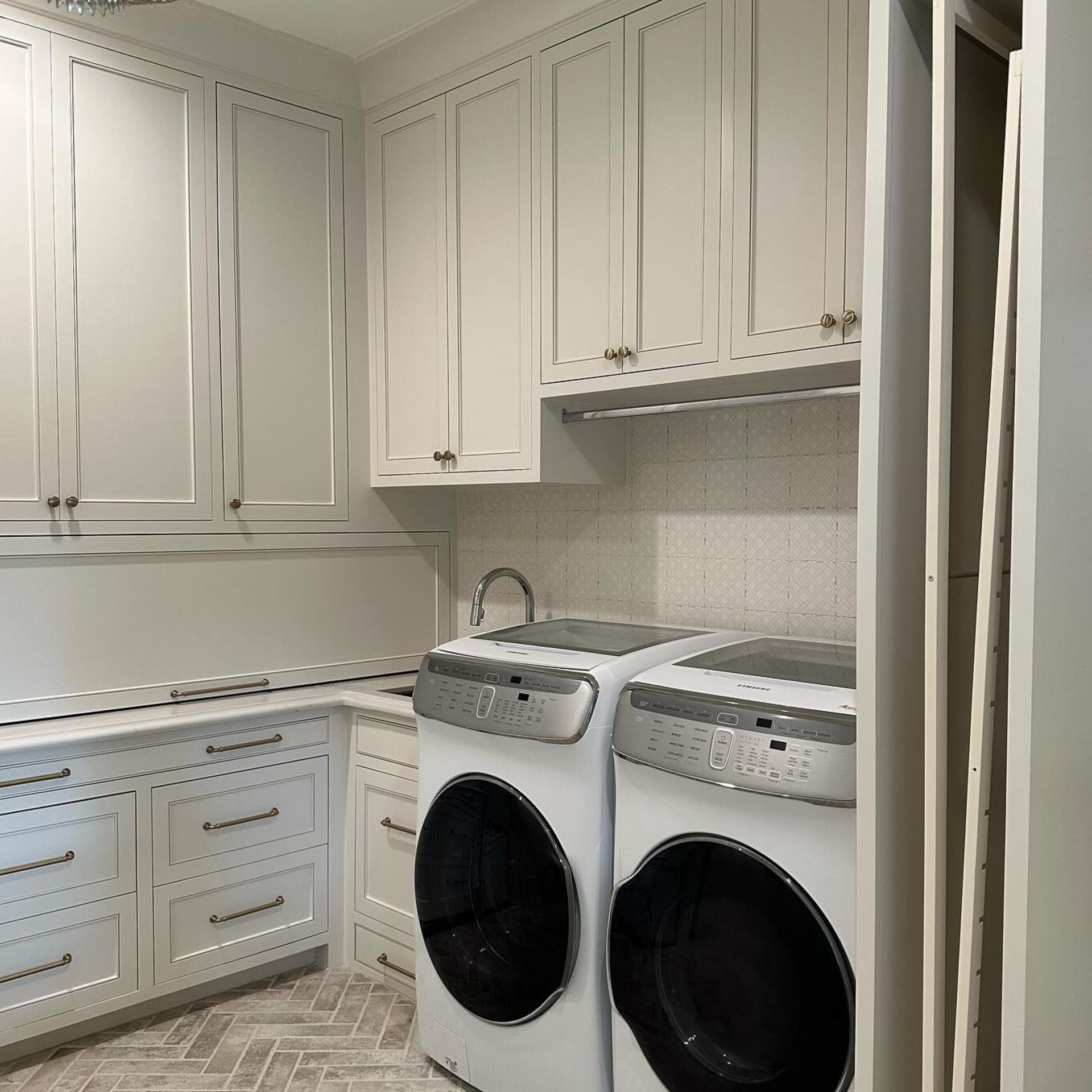 Modern white laundry room with cabinets, countertop, and side-by-side washer and dryer.