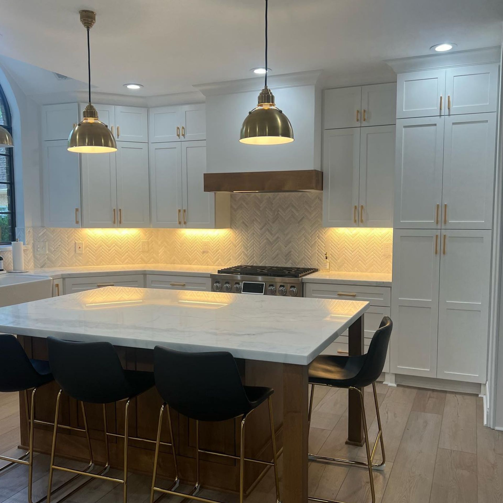 Modern white kitchen with marble island, pendant lights, and built-in cabinets