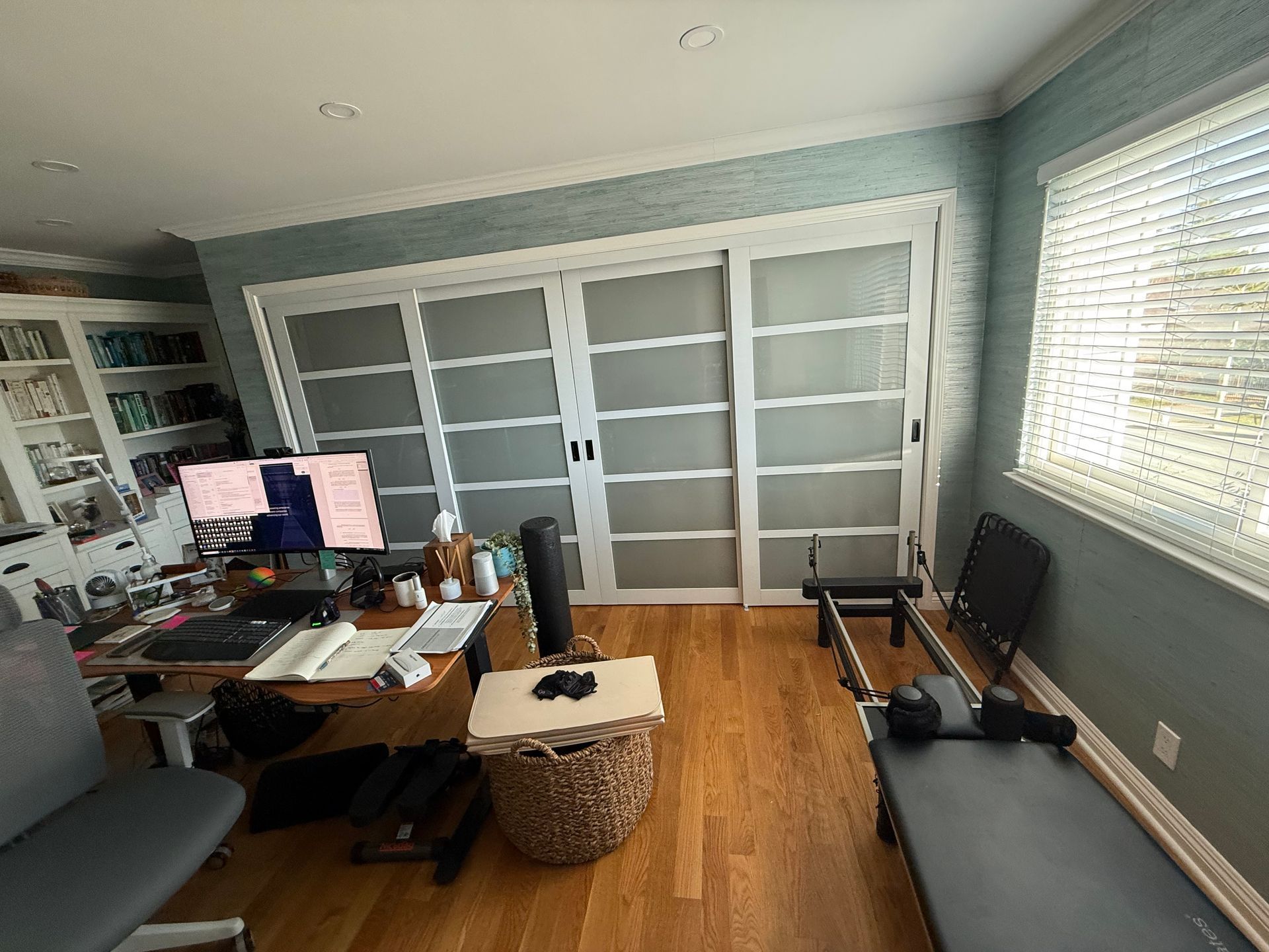A room with a desk , chair , computer and a bench.