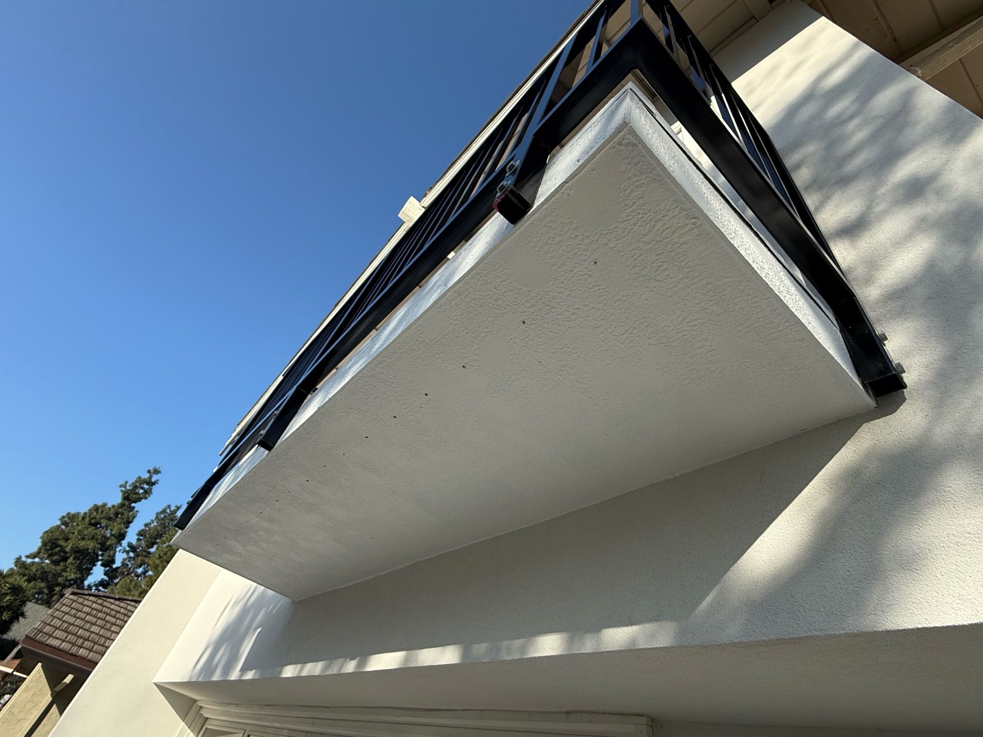A balcony on the side of a building with a blue sky in the background.