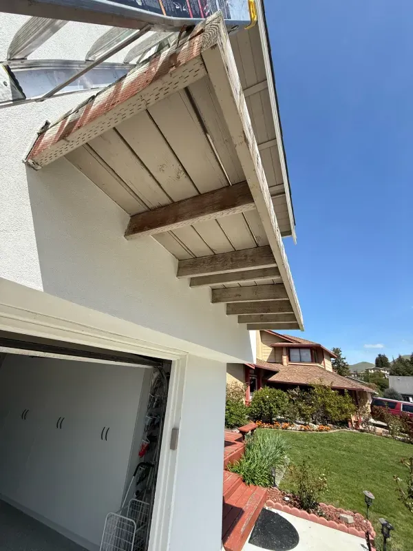 A white house with a roof that has a gutter on it.