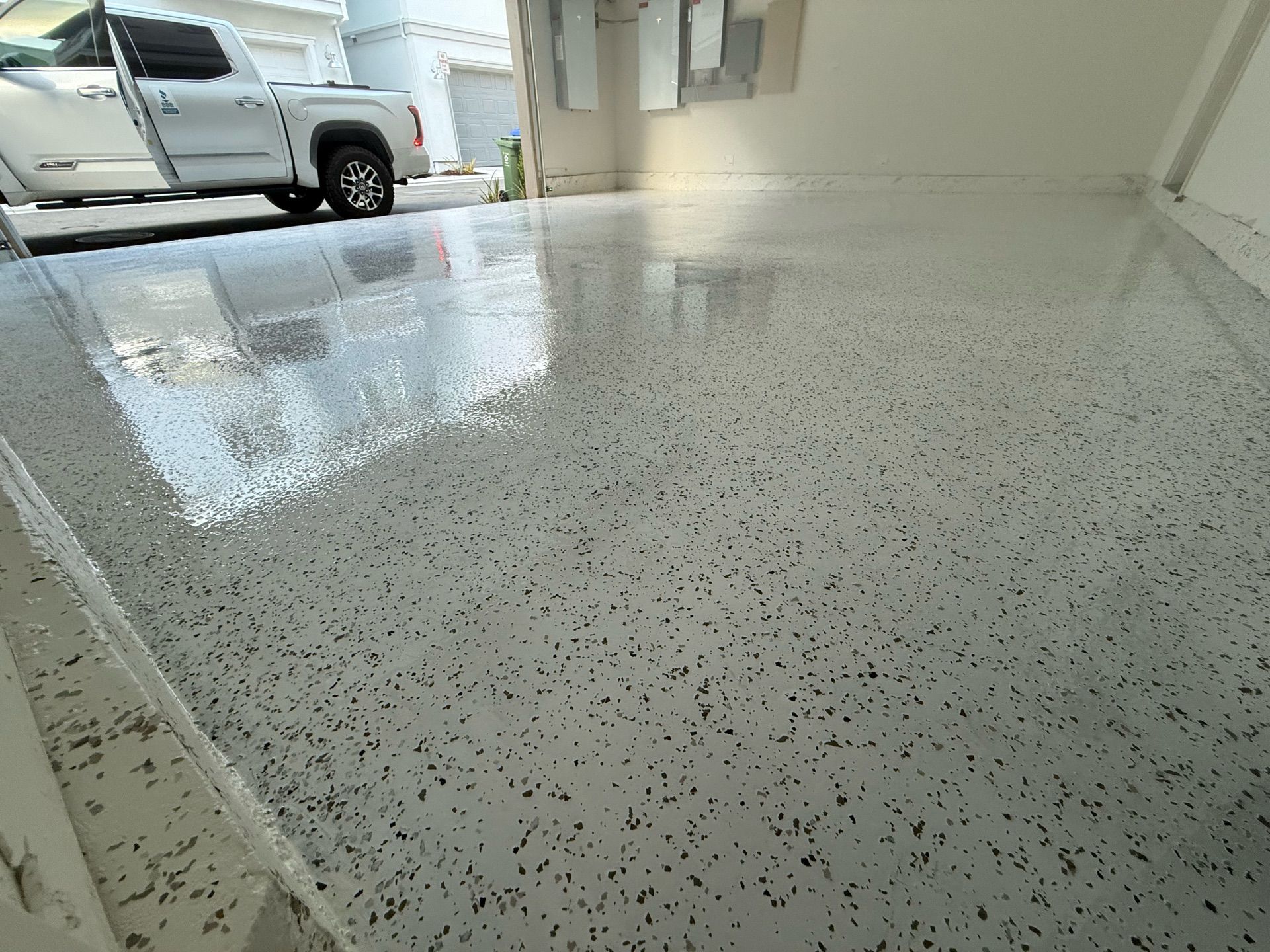 A white truck is parked in a garage with a shiny floor.