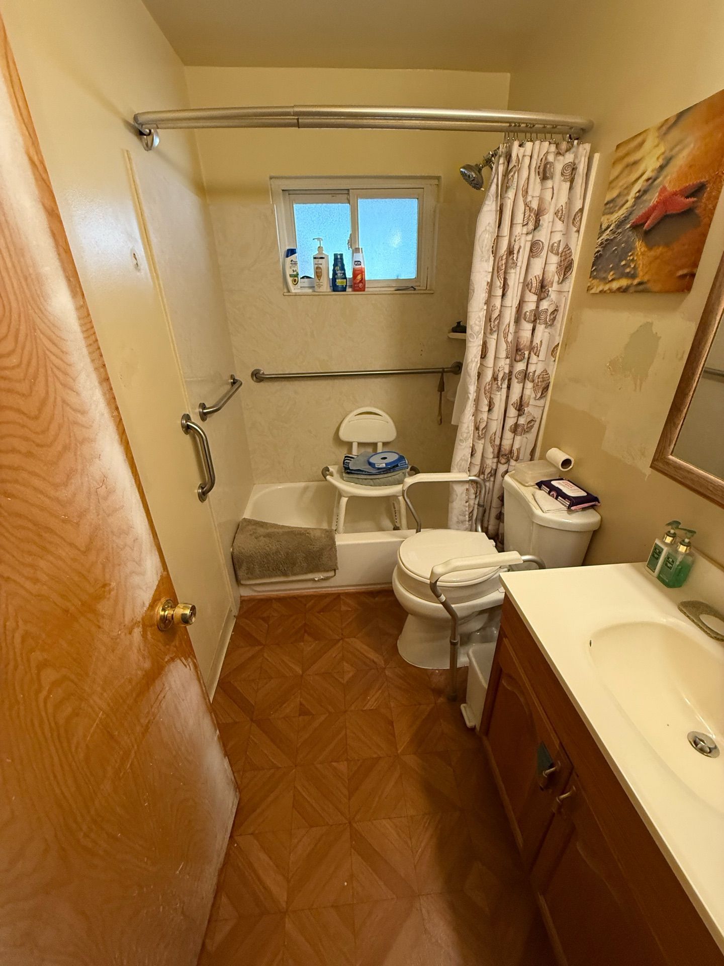 Small bathroom with a toilet, sink, bathtub, shower curtain, and window.