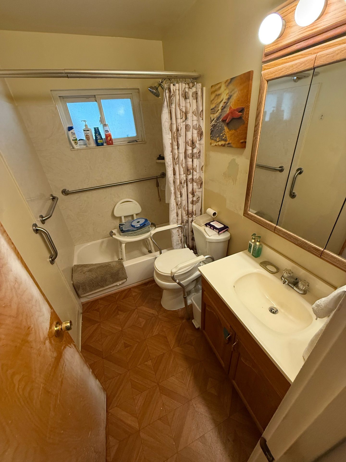 Small beige bathroom with toilet, sink vanity, mirror, towel bar, and shower curtain.