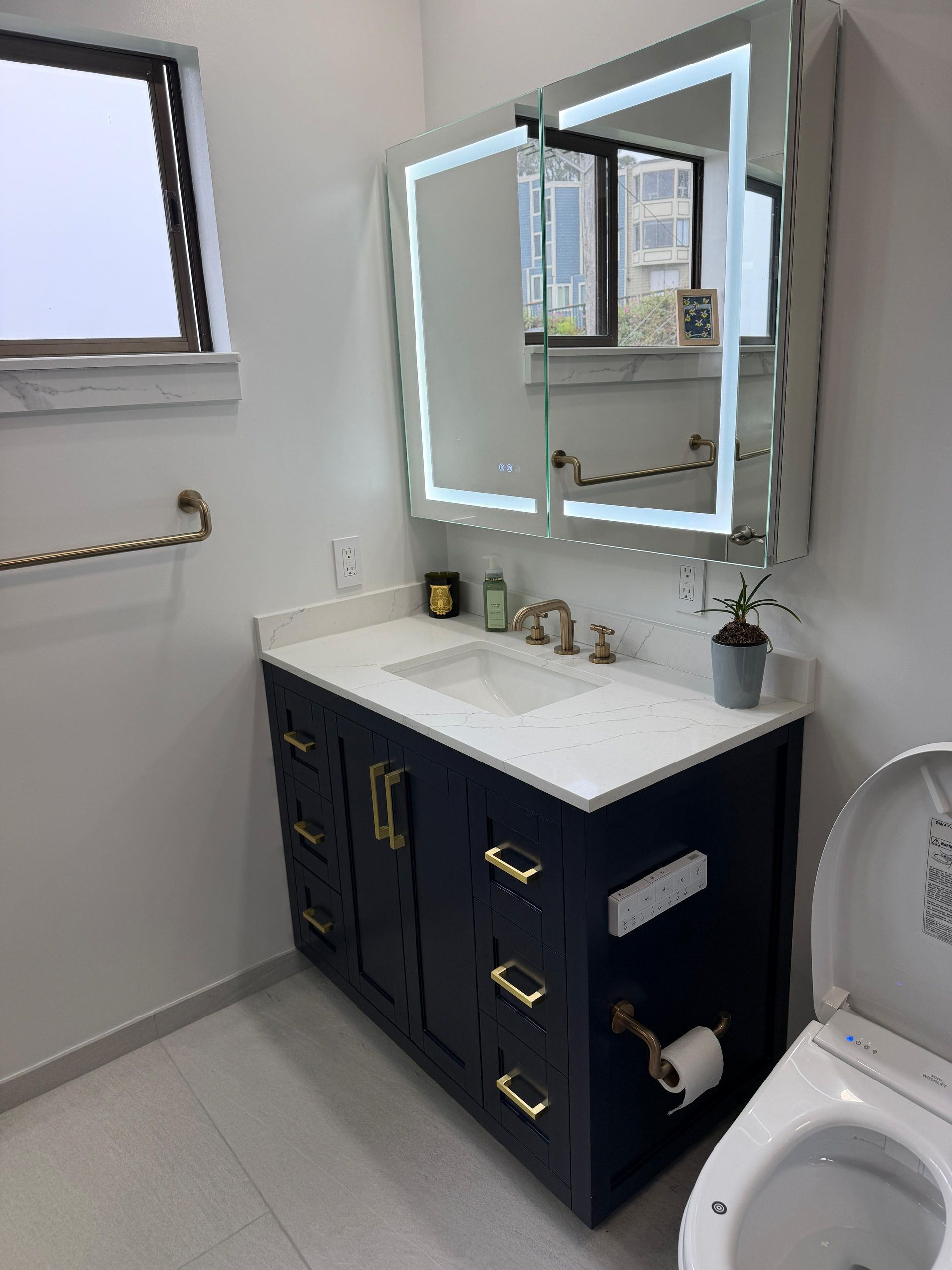 Complete bathroom renovation transforming an outdated bathtub into a spacious, modern walk-in shower with frameless glass enclosure, custom navy blue subway tile, decorative shower niche, brushed brass fixtures, rainfall showerhead, handheld shower system, built-in shower bench, grab bars for accessibility, and premium porcelain tile flooring. The remodel also features a custom navy shaker vanity with quartz countertop, integrated LED medicine cabinet, modern undermount sink, upgraded lighting, comfort-height smart toilet, and contemporary plumbing fixtures.
This bathroom remodel was designed to improve functionality, accessibility, storage, durability, and everyday comfort while adding lasting value to the home. Dream Build Services specializes in custom bathroom renovations using high-quality materials and craftsmanship tailored to each homeowner's style and needs.
Services Included:
• Bathroom Remodeling
• Bathroom Renovation
• Tub-to-Shower Conversion
• Walk-In Shower Installation
• Custom Tile Installation
• Frameless Glass Shower
• Quartz Countertop Installation
• Custom Vanity Installation
• LED Medicine Cabinet Installation
• Accessibility Bathroom Upgrades
• Plumbing Fixture Replacement
• Home Remodeling
• General Contractor Services