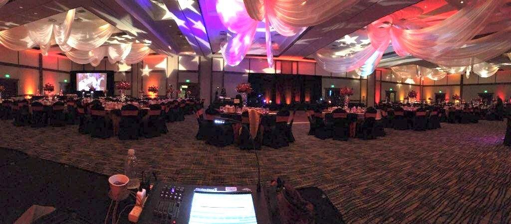 A large ballroom filled with tables and chairs and a laptop on a table.