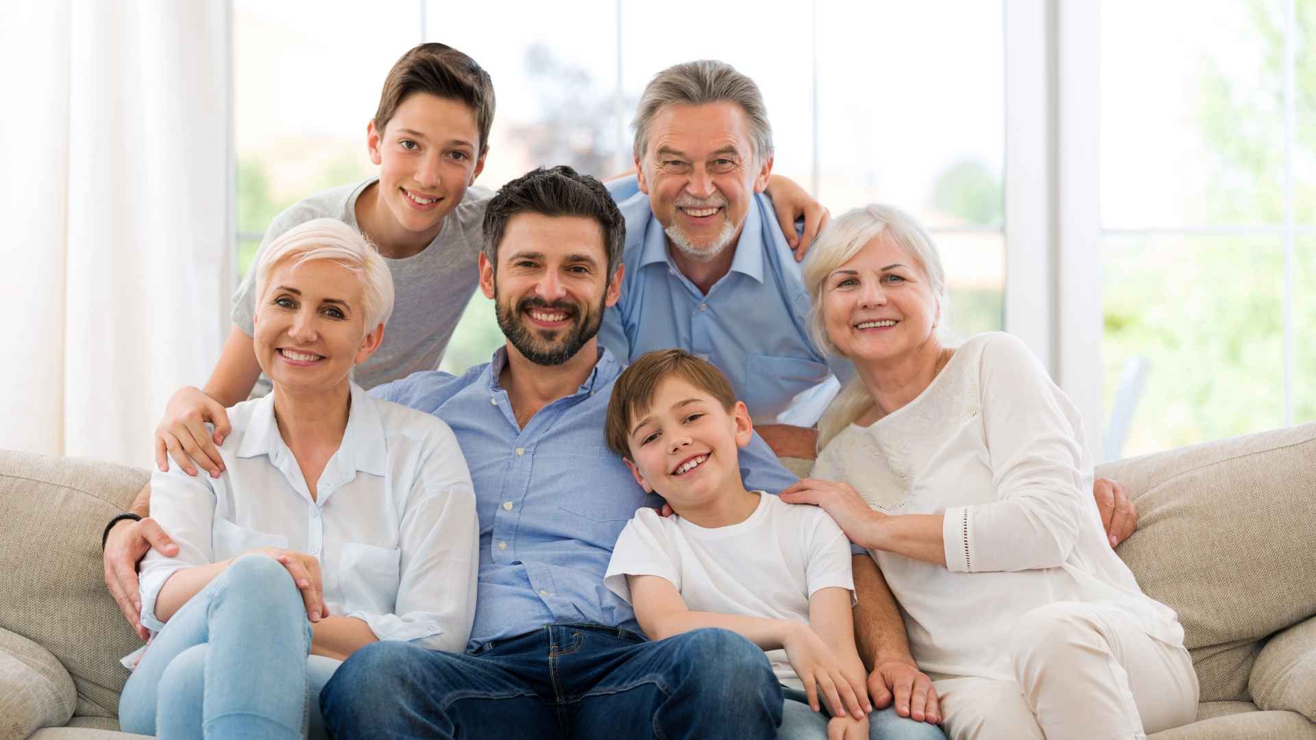 A large family is posing for a picture while sitting on a couch.