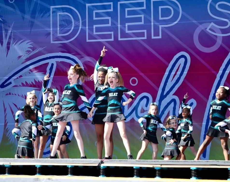 A group of cheerleaders are performing on a stage in front of a sign that says deep
