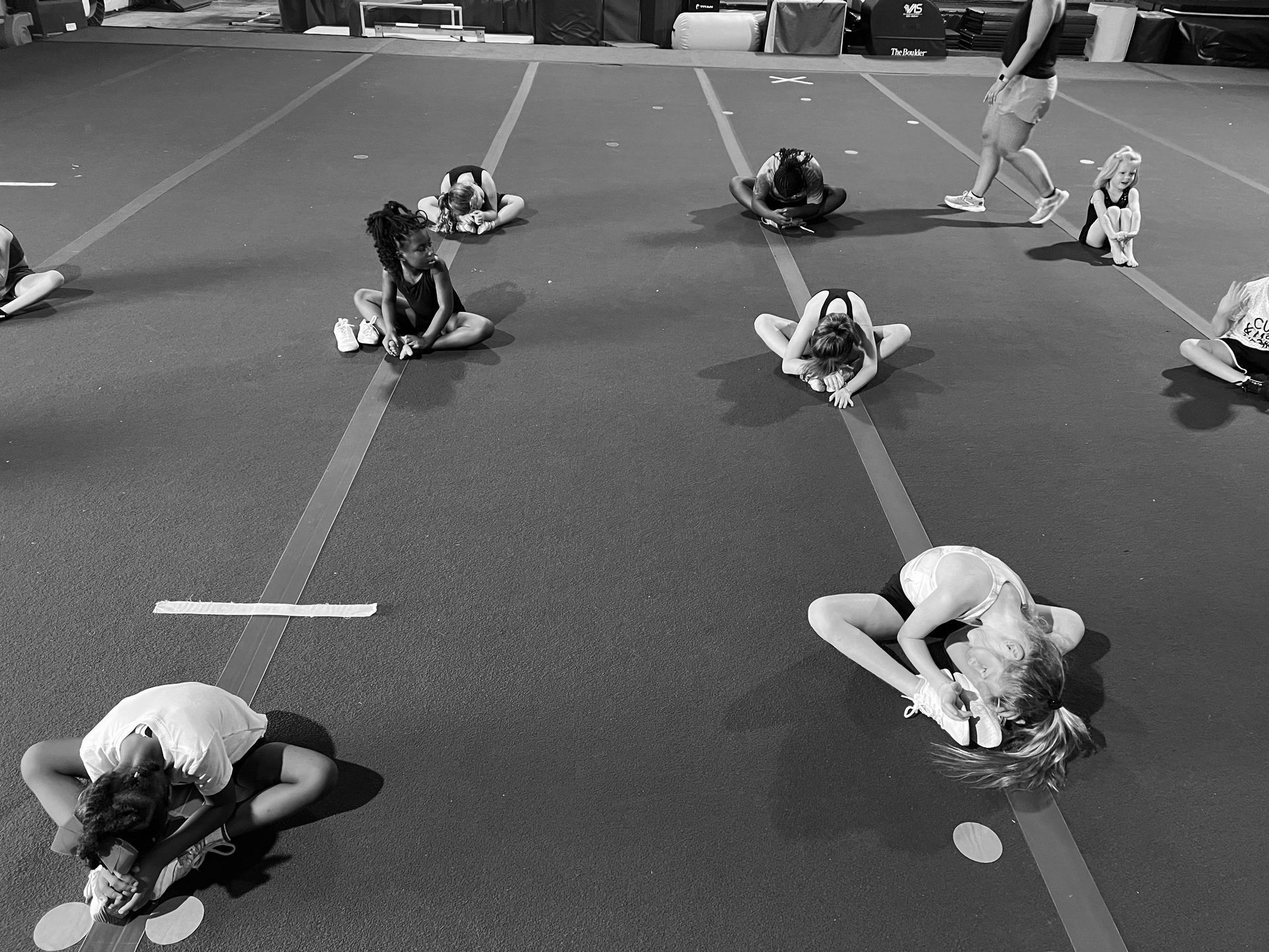 A group of girls are doing stretching exercises on the floor