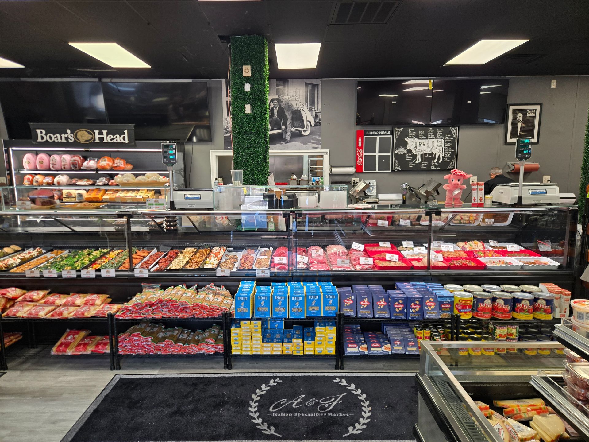 Grocery deli counter with packaged meats, cheeses, and snacks behind glass display cases.