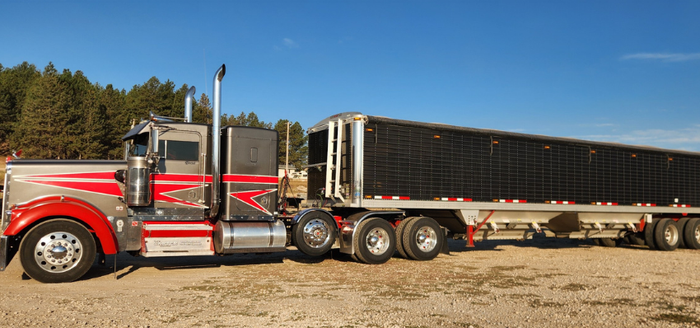 Green semi-truck hauling a red fire truck on a flatbed trailer. 