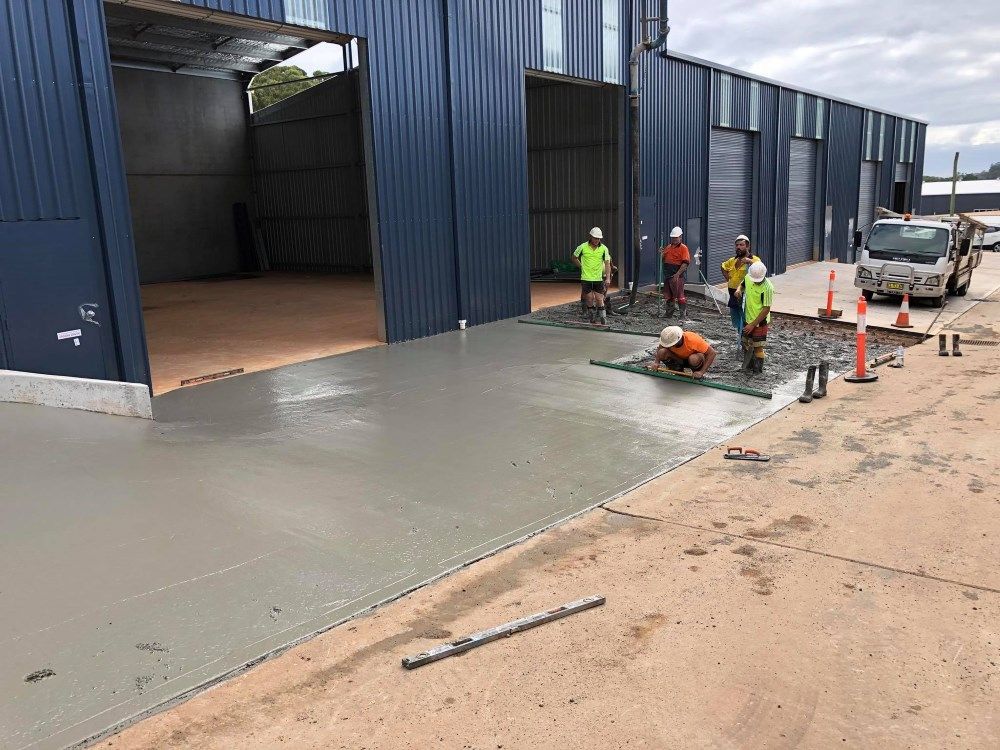 Construction Workers Are Working On A Concrete Driveway In Front Of A Building — Luke Seears Concreting in Lake Cathie, NSW