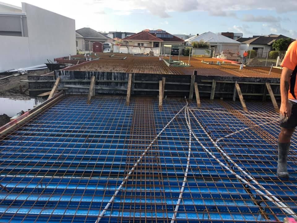 A Man Is Standing On Top Of A Blue Concrete Floor — Luke Seears Concreting in Lake Cathie, NSW